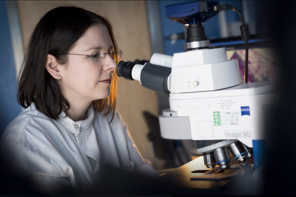 A woman looks into a microscope